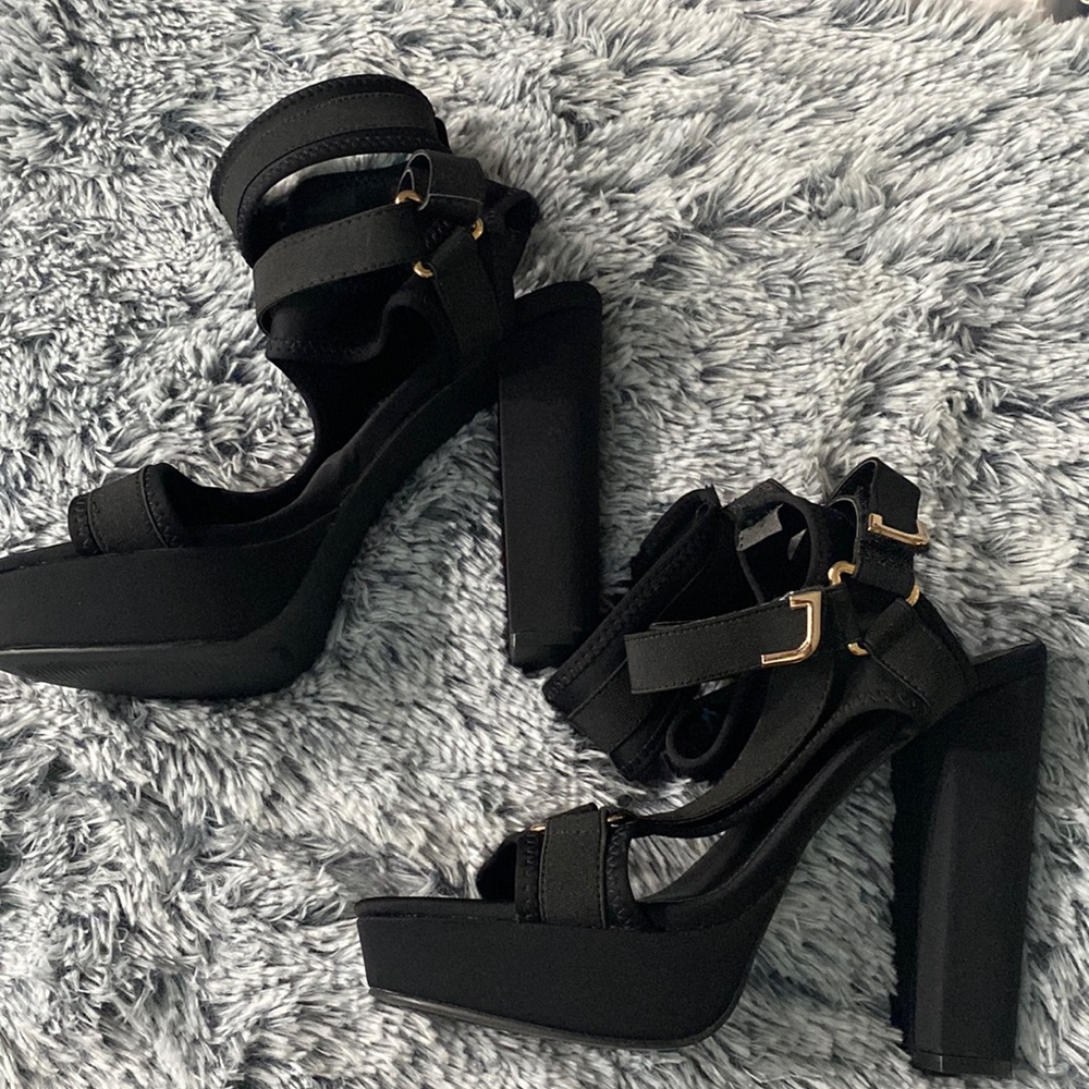 Fashion Nova black platform 5-inch heels, with velcro straps with gold buckles.